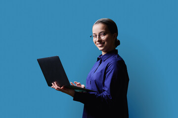 Teenage girl high school student using laptop on blue background