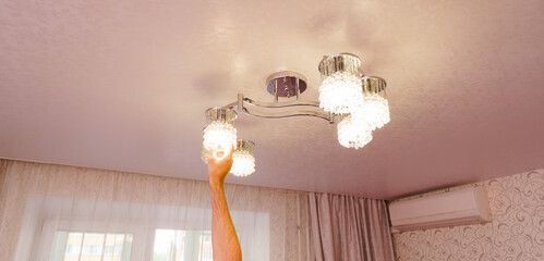 a man's hand will replace the bulbs in the chandelier lampshades. 