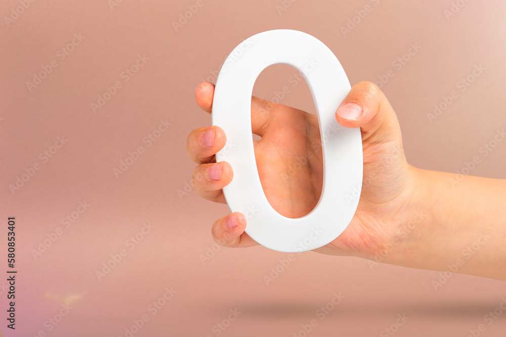 Fototapete Numeral zero in hand. A hand holds a white number zero on a red background with copy space. Zero concept, 0 percent interest rate, minimum air emissions, cost or credit no increase.