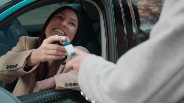 Video of car rental agency employee giving car keys to beautiful young woman.