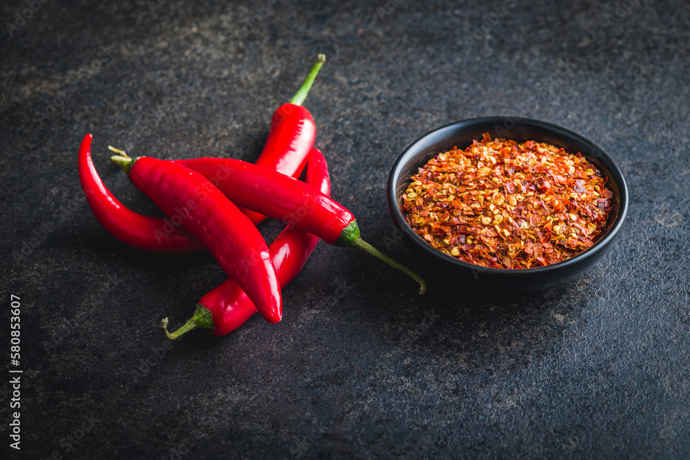 Sticker dry chili pepper flakes. crushed red peppers in bowl on black table.