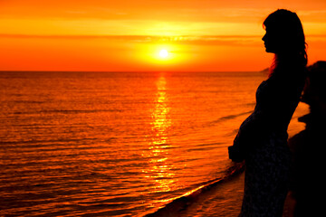 silhouette of a happy pregnant woman on the sea in the summer on the nature