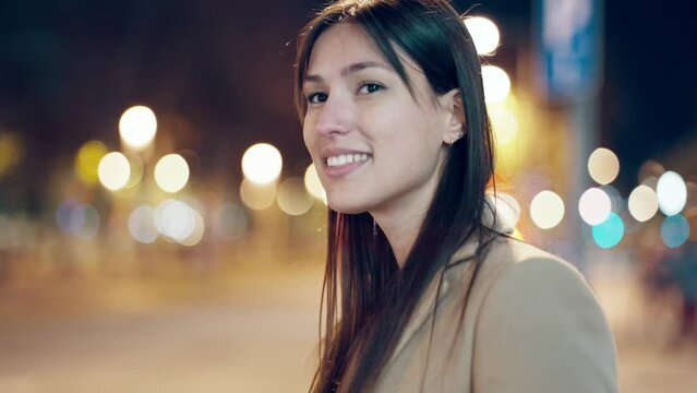 Video of attractive smiling young woman walking in the street at night.