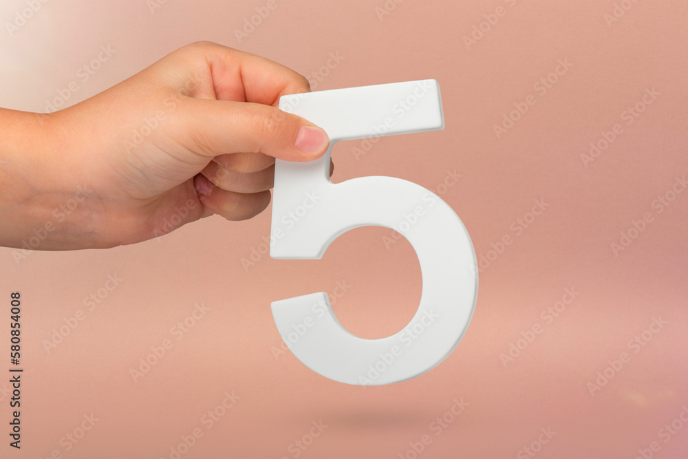 Leinwandbilder number five in hand. hand holding white number 5 on red background with copy space. concept with num
