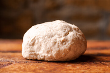 Yeast dough ball on wooden background. Cooked dough for baking pizza or bread.