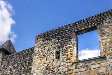 The view to the sky through a window without glass. Photographed through the window. Window without glass. Stone wall. Old house. View of the sky. Window hole. Camino de Santiago. The Way of St. James