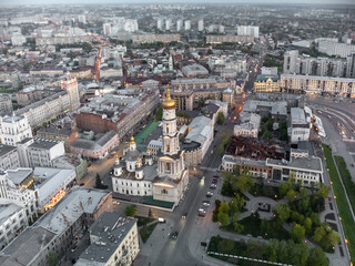 Aerial view of Dormition Cathedral with golden dome and streets in evening lights of Kharkiv city downtown, Ukraine.  Selective focus with blur
