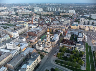 Aerial look down view on Dormition Cathedral and streets in evening lights of Kharkiv city downtown, Ukraine.  Selective focus with blur