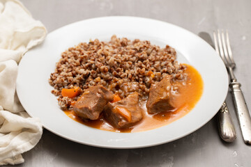 Boiled buckwheat with meat and sauce on white dish