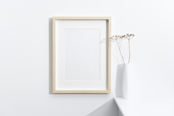 Portrait blank picture frame mockup in white room interior, wooden frame with copy space