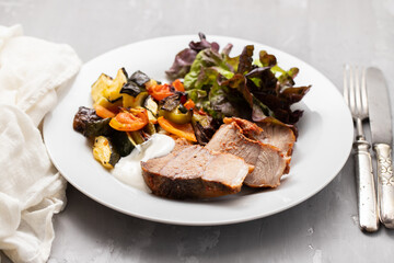 Baked pork with vegetables and fresh salad on plate