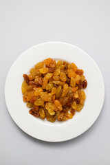 Yellow golden raisins in white ceramic plate