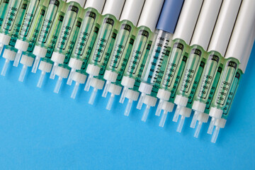 Diabetic insulin pens lined up on a blue background. Provision of medicines for patients with diabetes mellitus