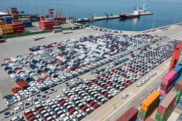 New assorted cars lined up in the port waiting to be loaded on the ro-ro (Roll on Roll off) vehicle car carrier ship. Aerial drone photo