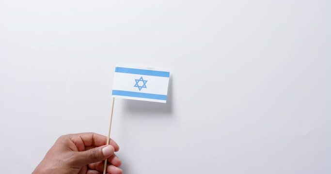Close up of hand holding flag of israel on white background with copy space