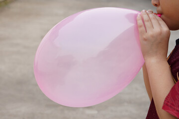 Closeup boy is blowing pink balloon, inflates  air to balloon Concept, children play, toy and...