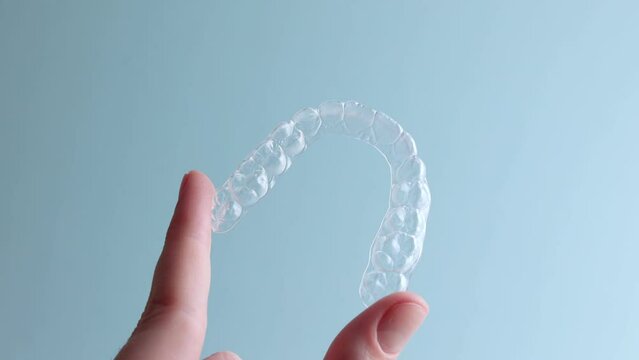 Aligners for aligning teeth on a blue background in a female hand