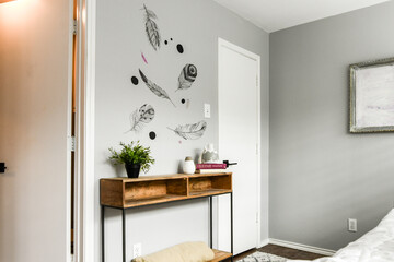 Gray wall with feathers painted on it and small table, neutral, 