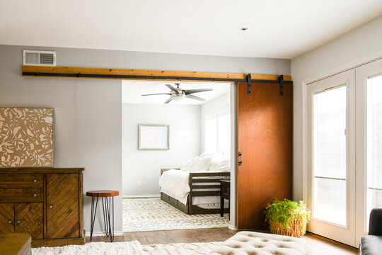 View from sliding door into neutral bedroom with single bed, rug, empty, natural light