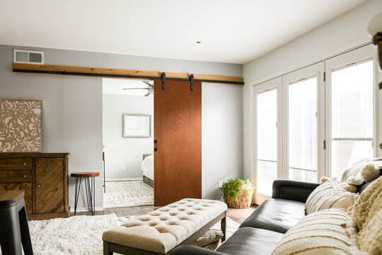 View from living room into to neutral bedroom with single bed, rug, empty, natural light