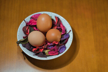Three eggs on a bed of flower petals in a bowl