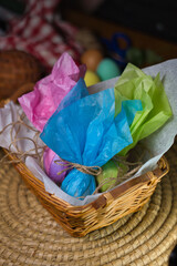 Three Easter eggs wrapped in colored paper inside a wicker basket