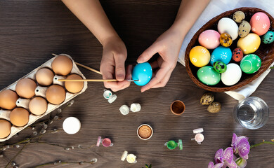 The process of coloring Easter eggs, female hands color eggs, top view.