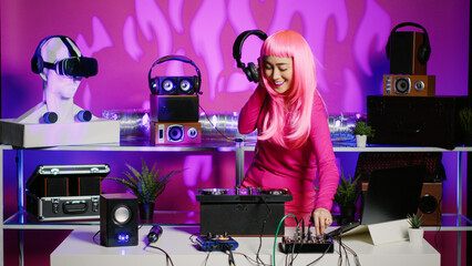Performer standing at dj table mixing techno sounds using professional mixer, performing music during night club concert. Asian artist listening audio while playing remix in studio