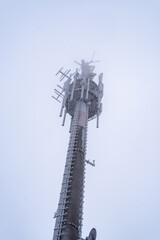 Obraz premium Cell tower covered in snow and ice on a foggy winter's day