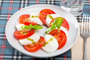 Fresh italian caprese salad with mozzarella and tomatoes on white plate