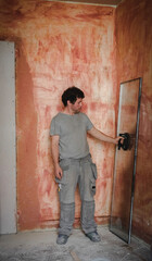 Caucasian man rests a window pane against a wall in a room.