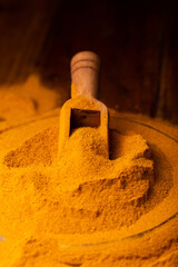 Turmeric Powder in a Wooden Spoon and Bowl