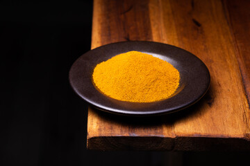 Turmeric Powder in a Wooden Spoon and Bowl