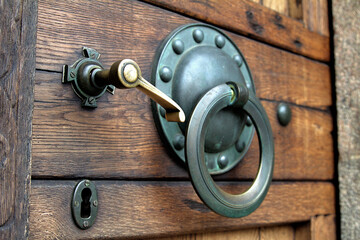 Antique forged bronze handle and ring on a wooden door