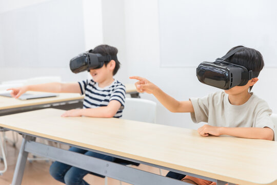 VRゴーグルをつけてゲーム・勉強をする小学生の男の子(VR・AR・MR)
