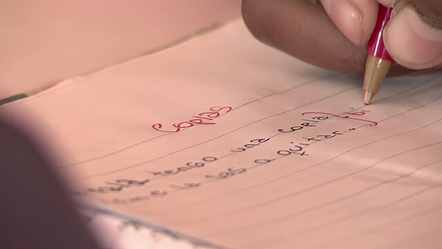 Hand of a Female Student Writing an Argentine Folk Couplet in Classroom. Close Up.  
