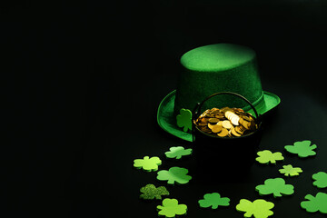 St. Patrick’s day, pot of gold coins, leprechaun hat and shamrocks, on black background, with...