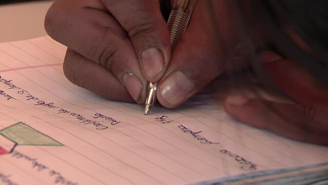 Hands of a Female Primary Student Writing "Roxana buys 9 kilos of meat" While Using the Rule of Three for Learning at School Class in Catamarca Province, Argentina. Close Up. 