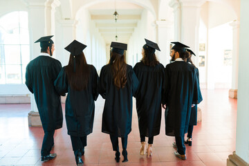 Friends graduates seen from behind with graduation gowns