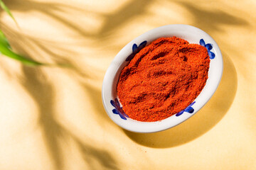 Tasty Spice: Paprika Powder in Ceramic Plate with Yellow Background and Natural Shades