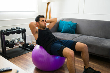 Sporty young man using a stability ball doing abdominal crunches