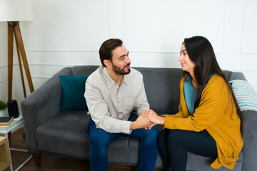 Beautiful couple smiling and holding hands at home