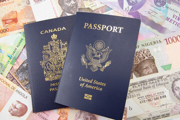 An American and Canadian passport on a background of African currency