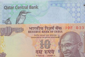 Fototapeta na wymiar An orange ten rupee bill from India arranged with a blue, purple and green riyal bank note from Qatar