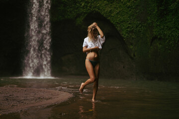Woman tourist at a waterfall in the tropical jungle, Bali.