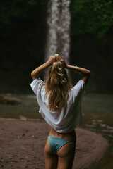 Naklejka premium Woman tourist at a waterfall in the tropical jungle, Bali.