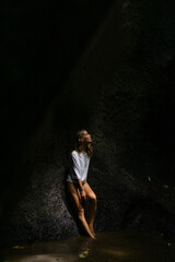 Woman tourist at a waterfall in the tropical jungle, Bali.