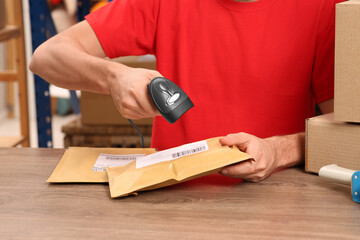 Post office worker with scanner reading parcel barcode at counter, closeup