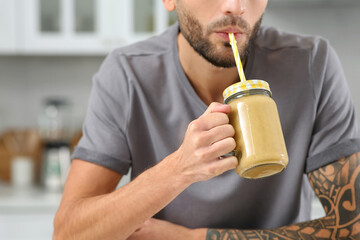 Man drinking delicious smoothie in kitchen, closeup