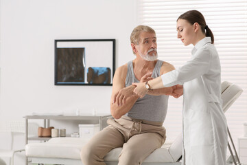 Obraz premium Orthopedist examining patient with injured arm in clinic